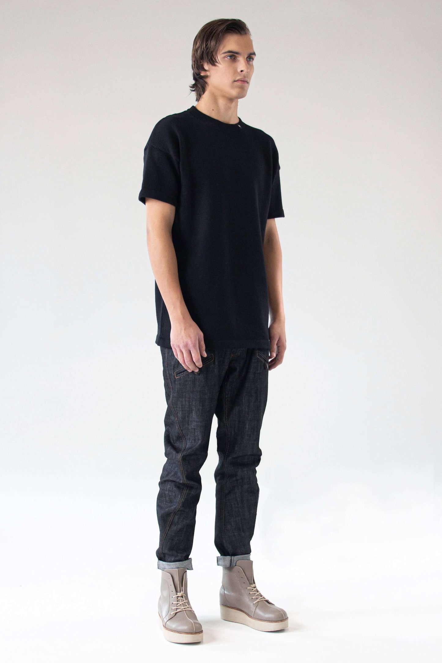 Front view of model wearing the One Wolf Knitted T-Shirt SEEKER in black, 100% cotton, unisex minimalist design