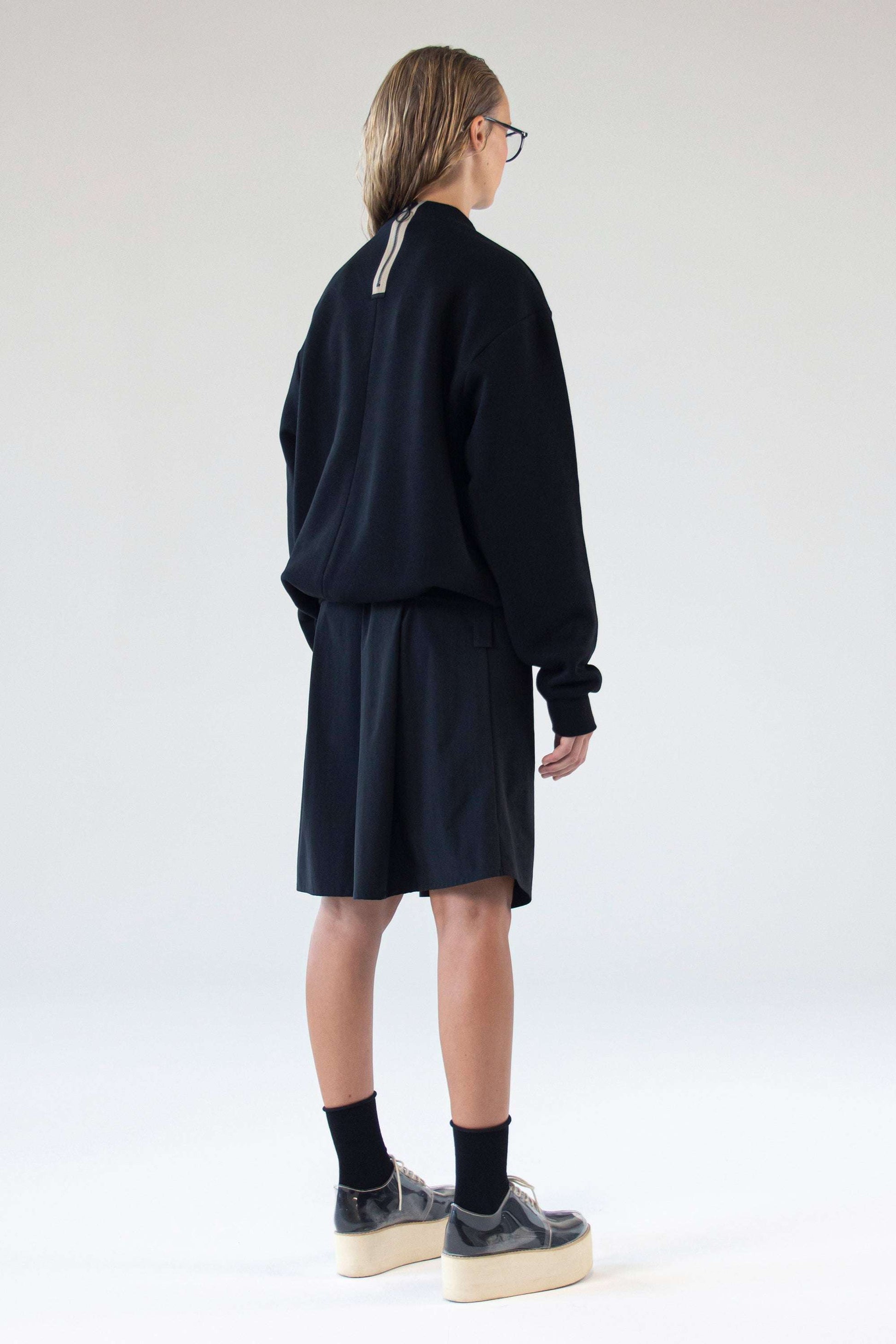 Back view of One Wolf unisex black sweater featuring signature vertical zipper detail.